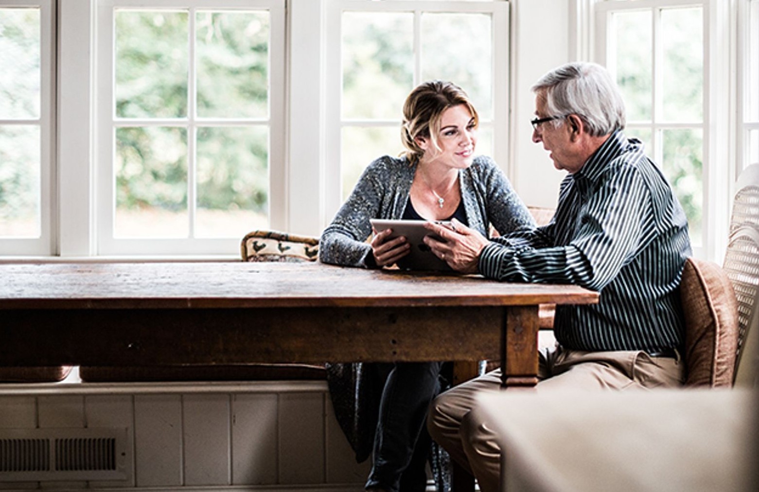 Older man being shown tablet by younger woman